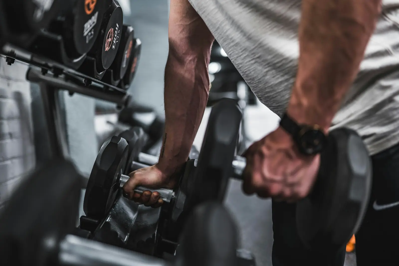 Athlete resting between intense sets with gym equipment in background